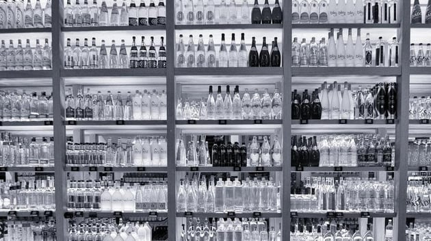 A shelf filled with various bottled waters.